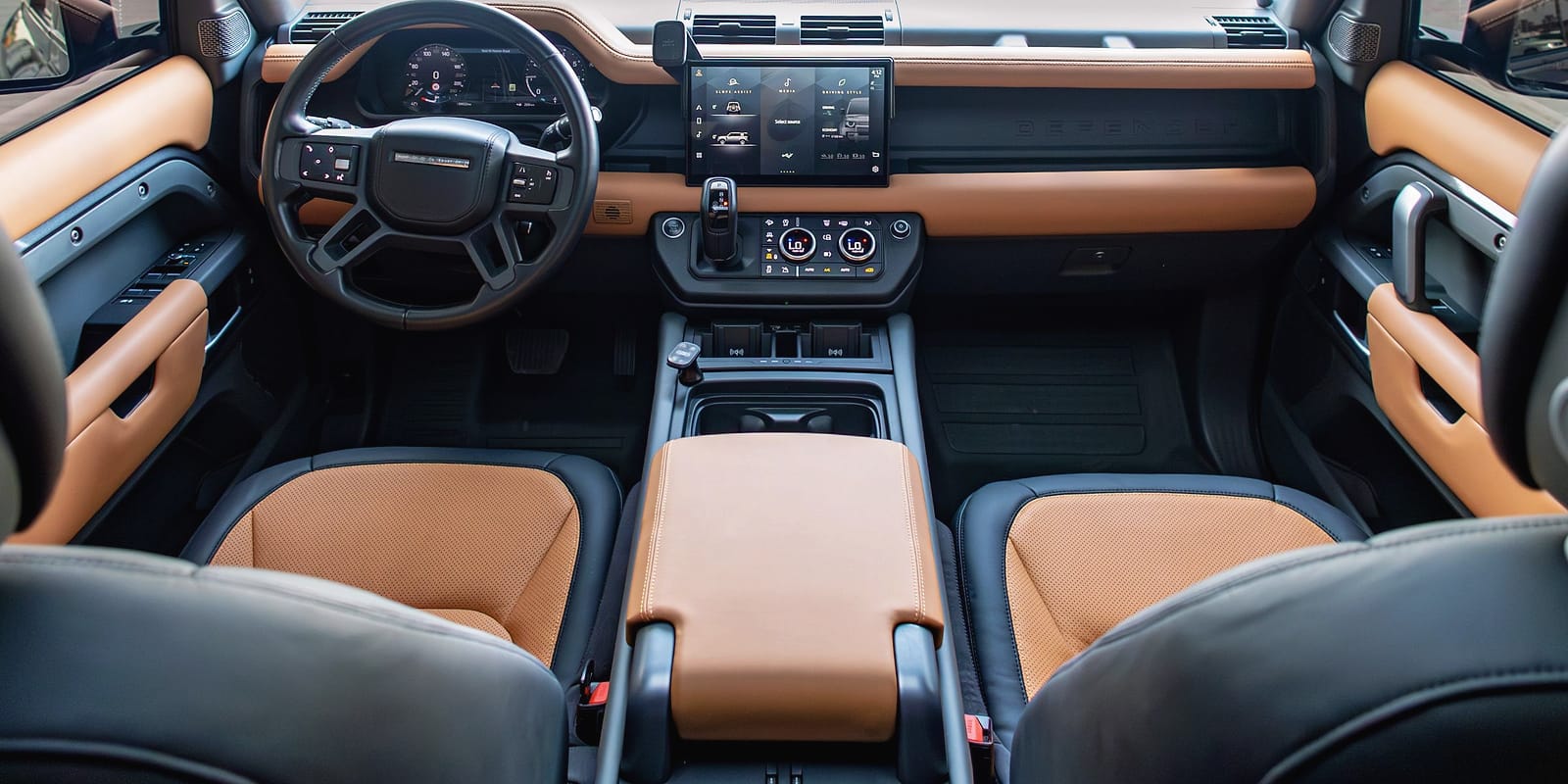 The Defender's cabin in black and tan leather, under a glass roof.