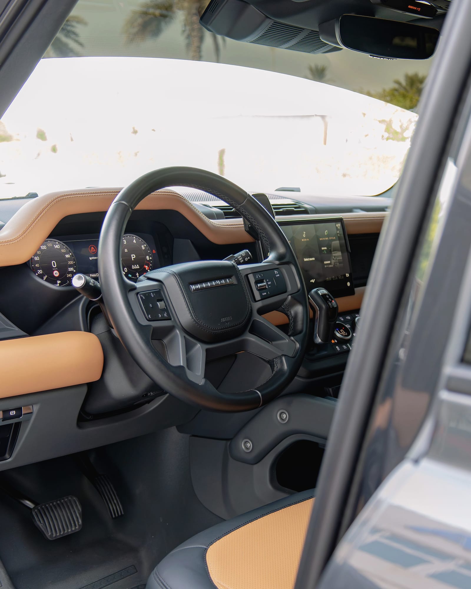 The Defender's steering wheel and dashboard through the open door.