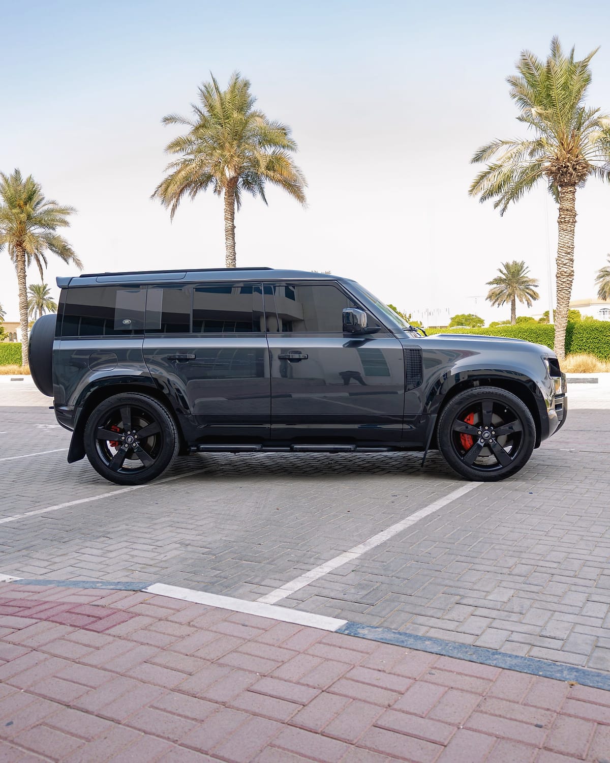 The Defender 110 in profile, with black wheels and red callipers.