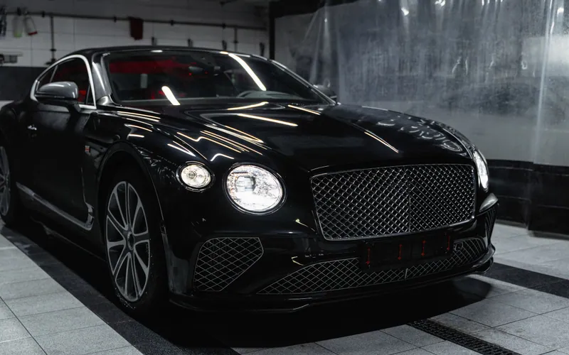 A black Bentley Continental GT in a dark bay.